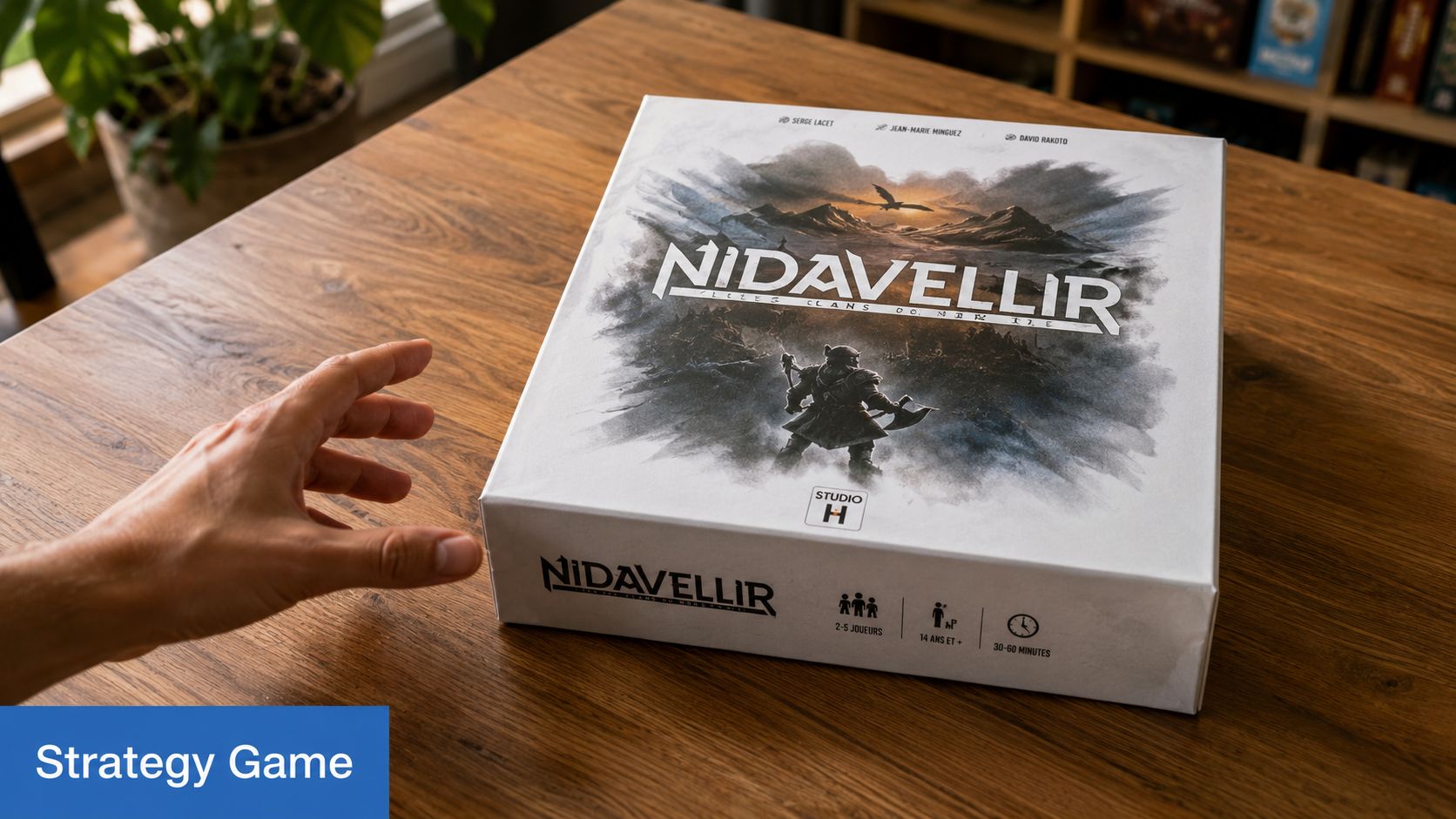Une main s'approche d'une boîte du jeu de société Nidavellir posée sur une table en bois.
